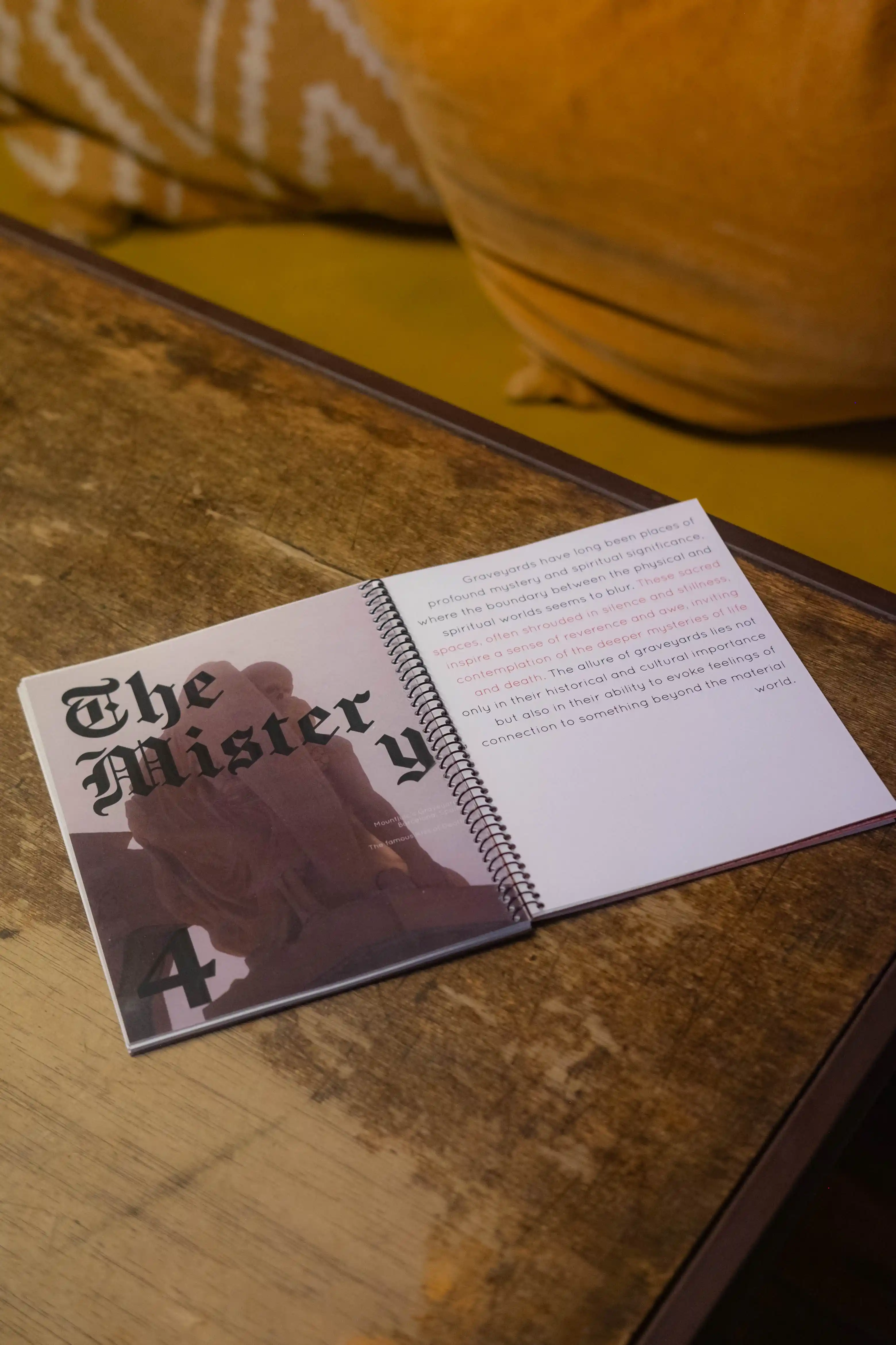 Spiral-bound Concession Perpetuelle book open at 'The Mistery' chapter, on a worn wooden table